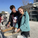 Martine outside serving food, smiling with another club member